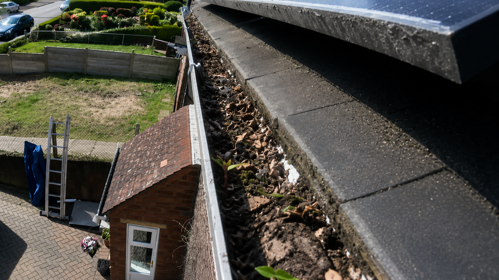 Before gutter cleaning — compacted debris and leaf matter blocking a Birmingham gutter channel